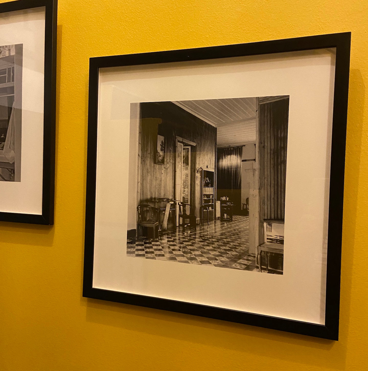 Détail d'un cadre photo posé sur un mur jaune, apportant une touche de couleur et de personnalisation à l'espace.