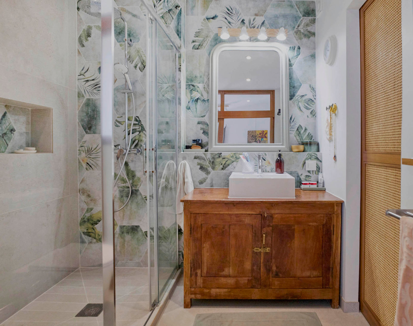 Aménagement d'une salle de bain avec douche à l'italienne, meuble en bois et carrelage à motif naturel, créant une ambiance chaleureuse et moderne.