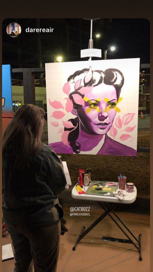 Cathryn Bozone live painting at night in front of a crowd.