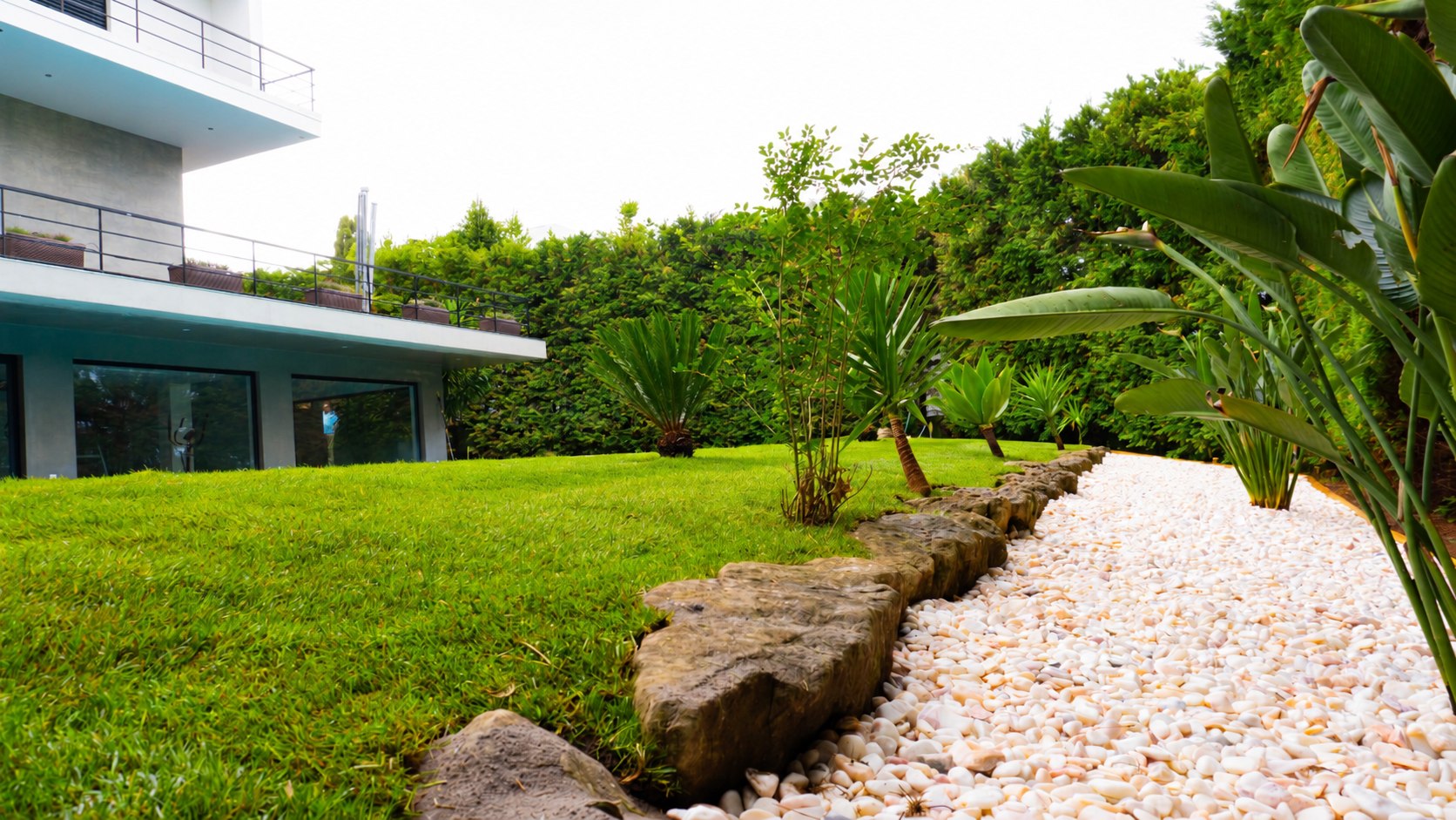 Jardim com relvado, plantas tropicais e caminho de seixo branco decorativo – paisagismo em Lisboa