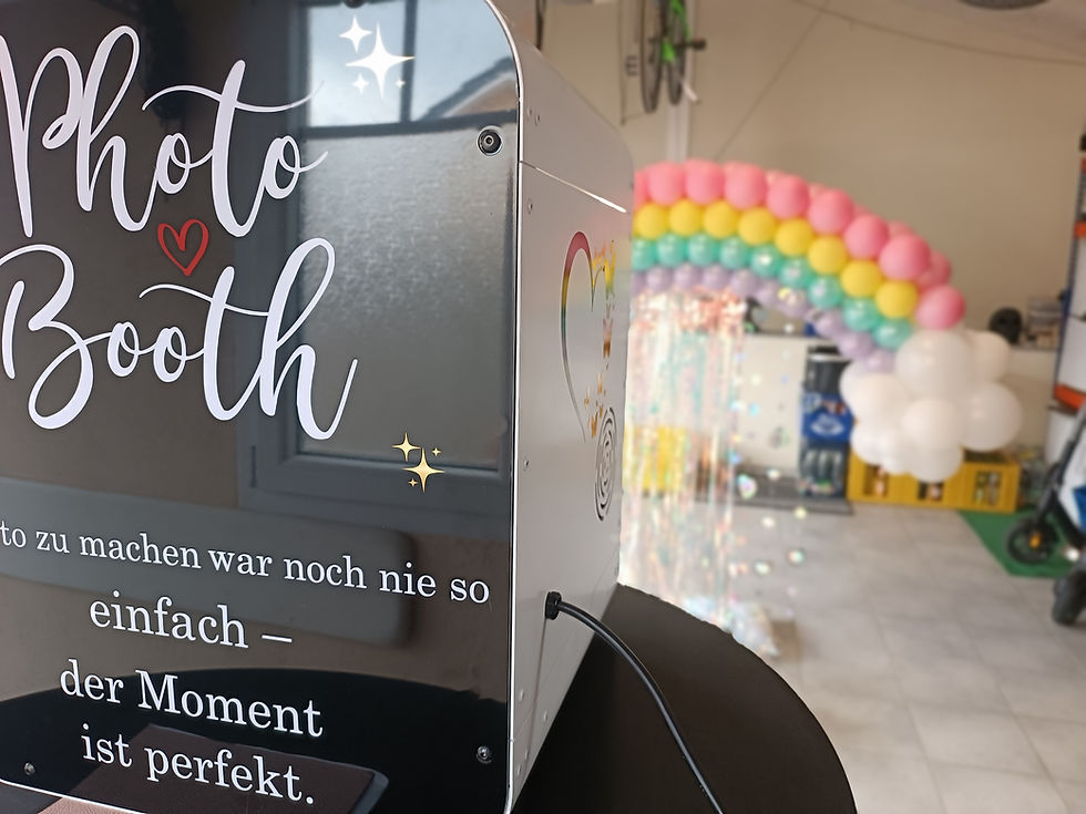 Eine Geburtstagsfeier an einem regnerischen Tag mit einer Fotobox und einem Regenbogen als Hintergrund.