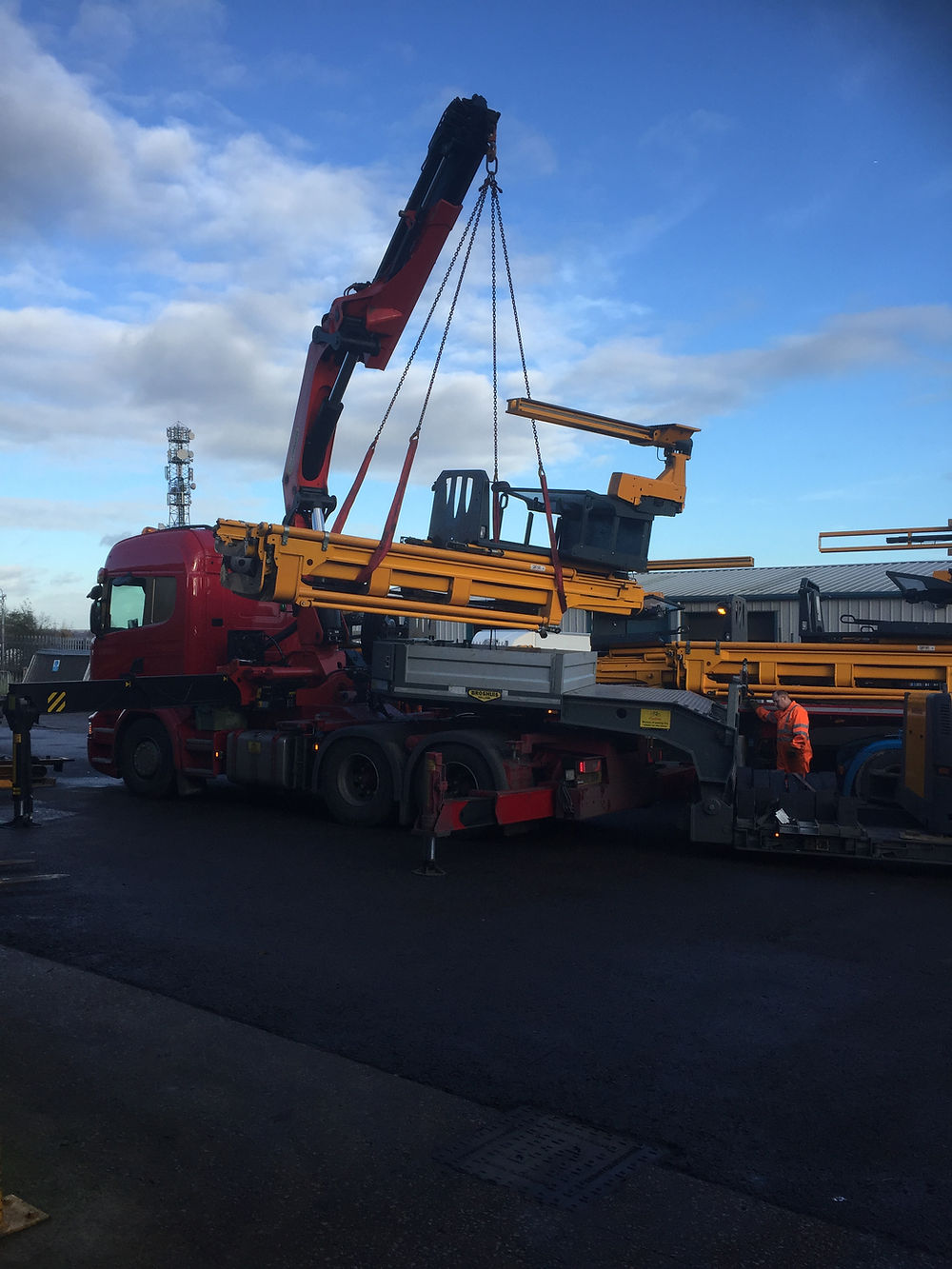 Crane truck loading a used VNA forklift for transport