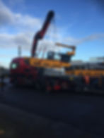 Crane truck loading a used VNA forklift for transport