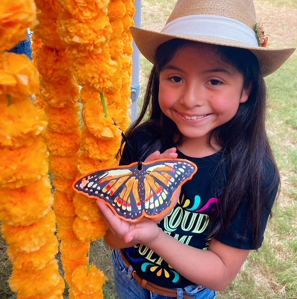 Happy little girl holding up her hand painted monarch message butterfly