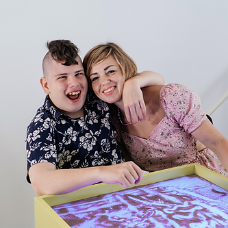 A young boy with CP has his arm a woman in a pink top
