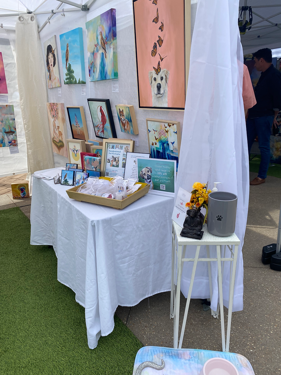 Outdoor art booth with colorful animal portraits, butterfly paintings, and signs for custom pet portraits under a white canopy. Cary, NC artist vendor tent set up