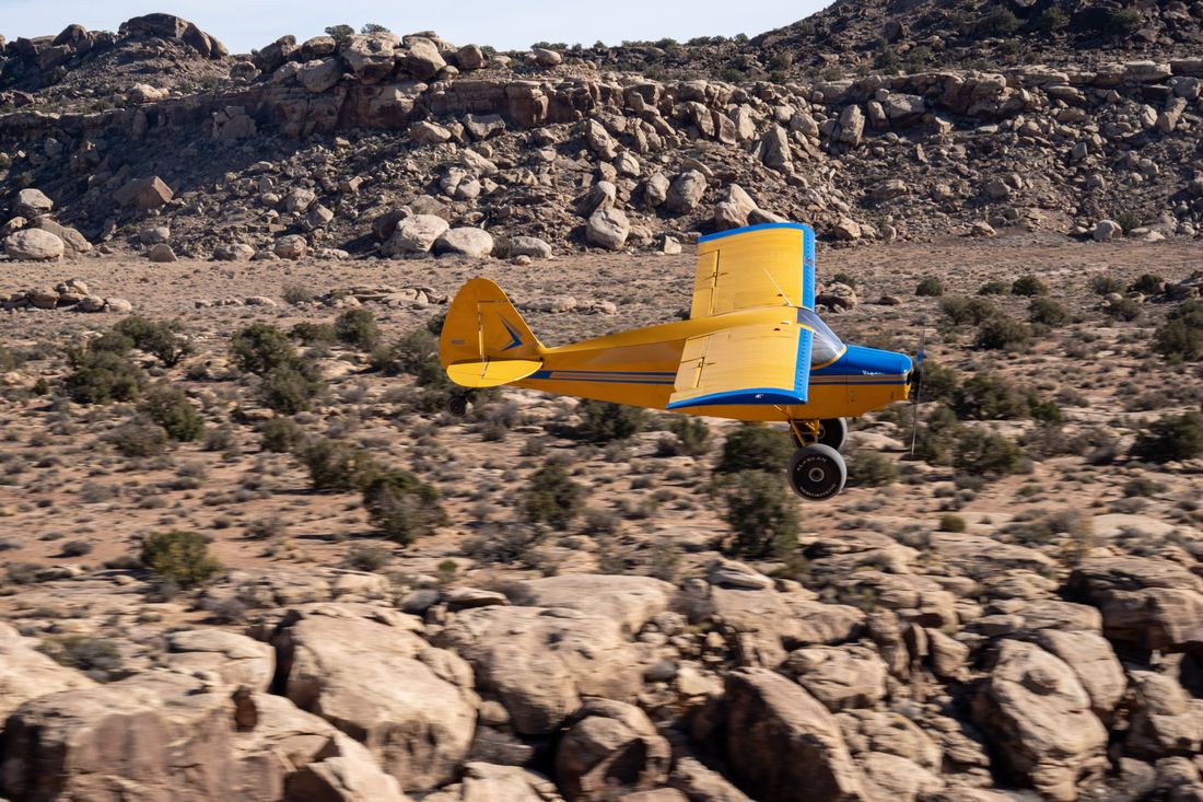 A yellow plane flying low over the Utah desert
