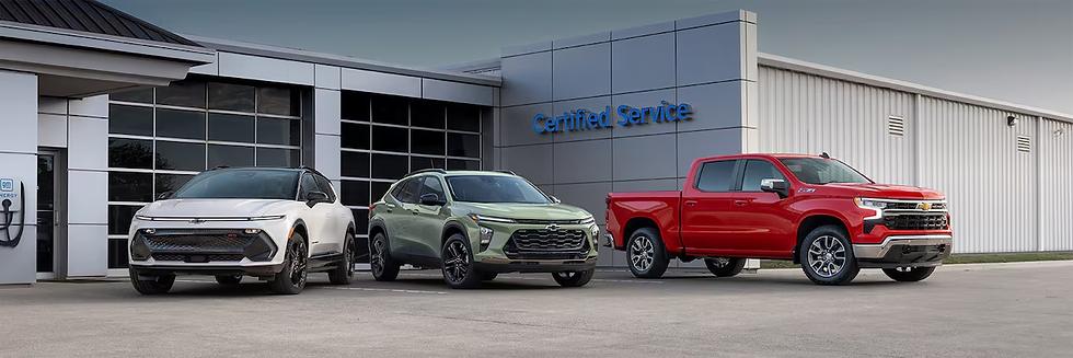 Three Chevrolet vehicles—white SUV, green crossover, red pickup—parked outside a service center. "Certified Service" sign in blue.