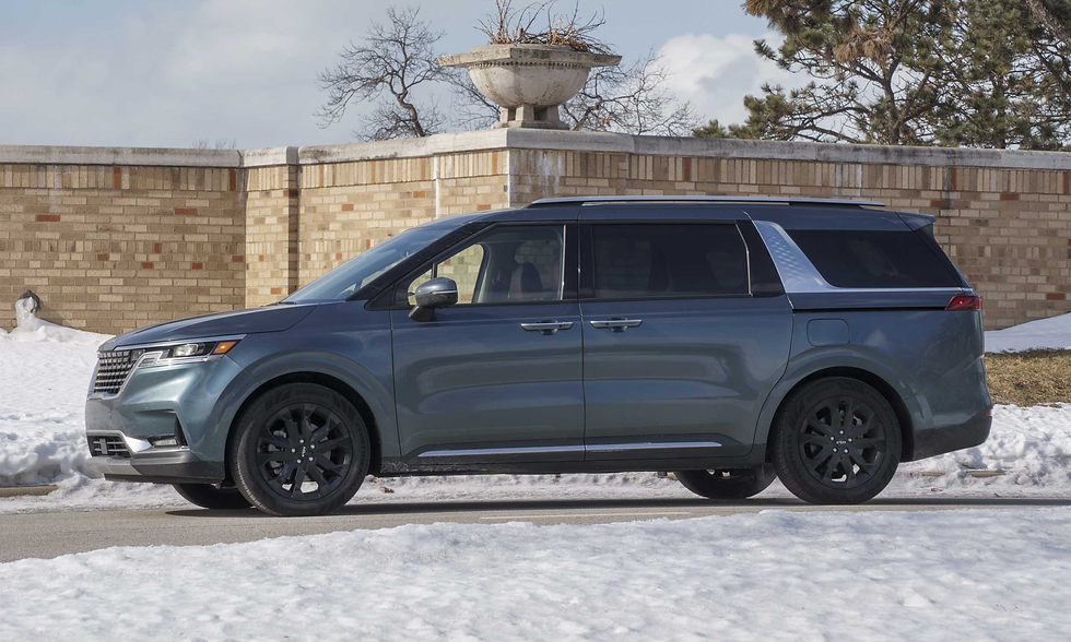 Blue SUV parked on snowy street next to a brick wall. Overcast sky and bare trees enhance the winter setting. Black wheels stand out.