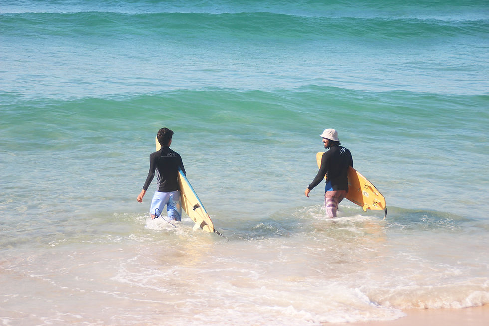 Dois surfistas entrando no mar de águas cristalinas em Grumari