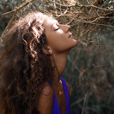 Person dressed in cobalt blue singlet top looking towards the sun with a tranquililty