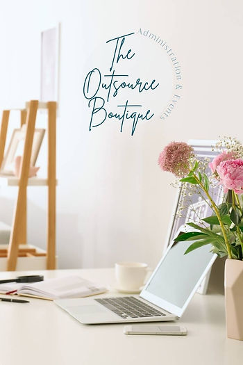 a minimalist office space in white with a timber A-frame bookshelf and white desktop with an open laptop on it. a musk pink vase holds some pink carnation flowers and a vertical stacked logo with the words The Outsource Boutique is on the wall of the room