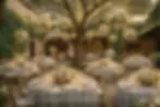Rustic wedding table setup at a Masia near Barcelona for 75 guests. A luxurious wedding dinner in the courtyard of an old villa in Spain. Round tables with white tablecloths, hanging floral arrangements on trees, and gold tableware. Wedding planning by Casamiga Weddings.