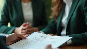 Arraigo Social Spain 2026 — документы и требования для получения ВНЖ. Юристы с клиентами в деловых костюмах за столом обсуждают документы. На переднем плане ручка и бумаги. Окно с размытым зеленым видом.