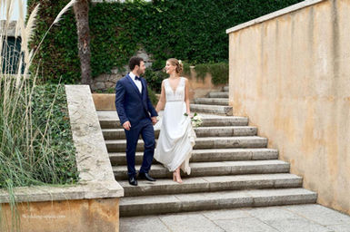 Bride and groom walking hand in hand on stone stairs at a romantic venue in Blanes (Costa Brava) – Casamiga Weddings Spain