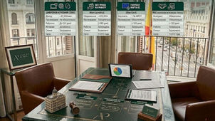 Сравнительная таблица всех ВНЖ Испании 2026: DNV, Non-Lucrativa, Blue Card, PAC. Офис с видом на улицу, на столе планшет с диаграммой, документы, миниатюрное здание и печать. На окне диаграммы о ВНЖ Испании. Офисный стол с планшетом, графиками и документами; на фоне баннер о сравнении виз DNV, Non-Lucrativa, Blue Card, PAC.