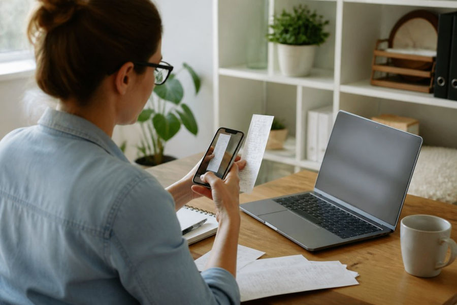 Small business owner using a smartphone to scan receipts to track business expenses on a digital dashboard