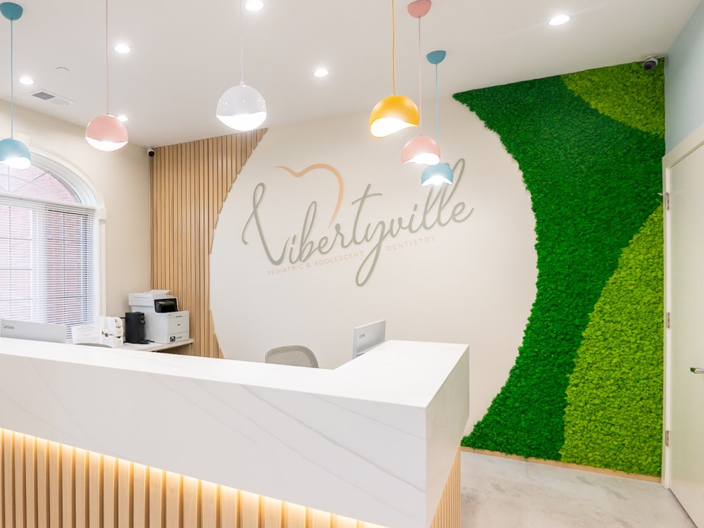 Reindeer moss feature wall with Libertyville Pediatric Dentistry branding in a bright reception area