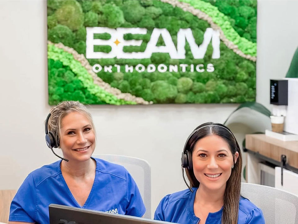 BEAM Orthodontics dental staff in treatment room with moss wall branding creating professional orthodontic care environment