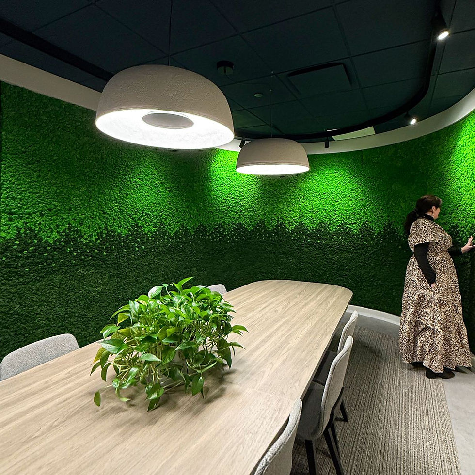 Person standing beside curved gradient reindeer moss wall in modern conference room with pendant lighting and oval meeting table