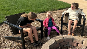 children sitting in Adirondack chairs