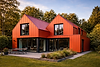 GreenCoat PLX red standing seam metal roof and cladding on modern house showing consistent coated steel finish in Ireland