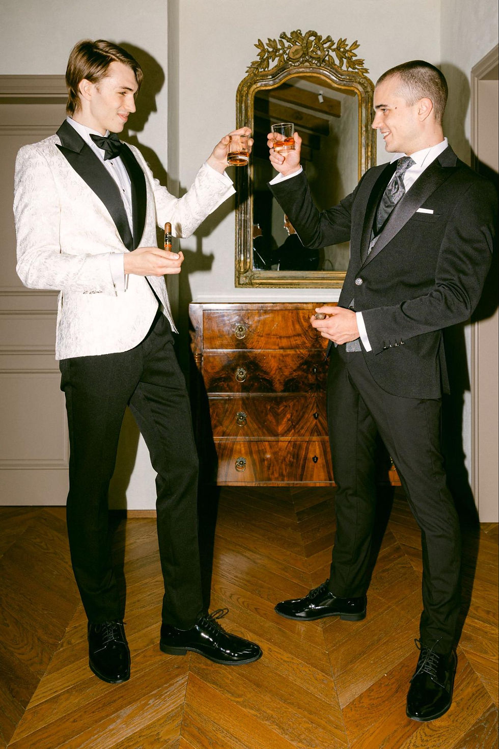 Mladoženja u bijelom i kum u crnom odijelu pokazuju elegantan kontrast i jasnu razliku u formalnosti.