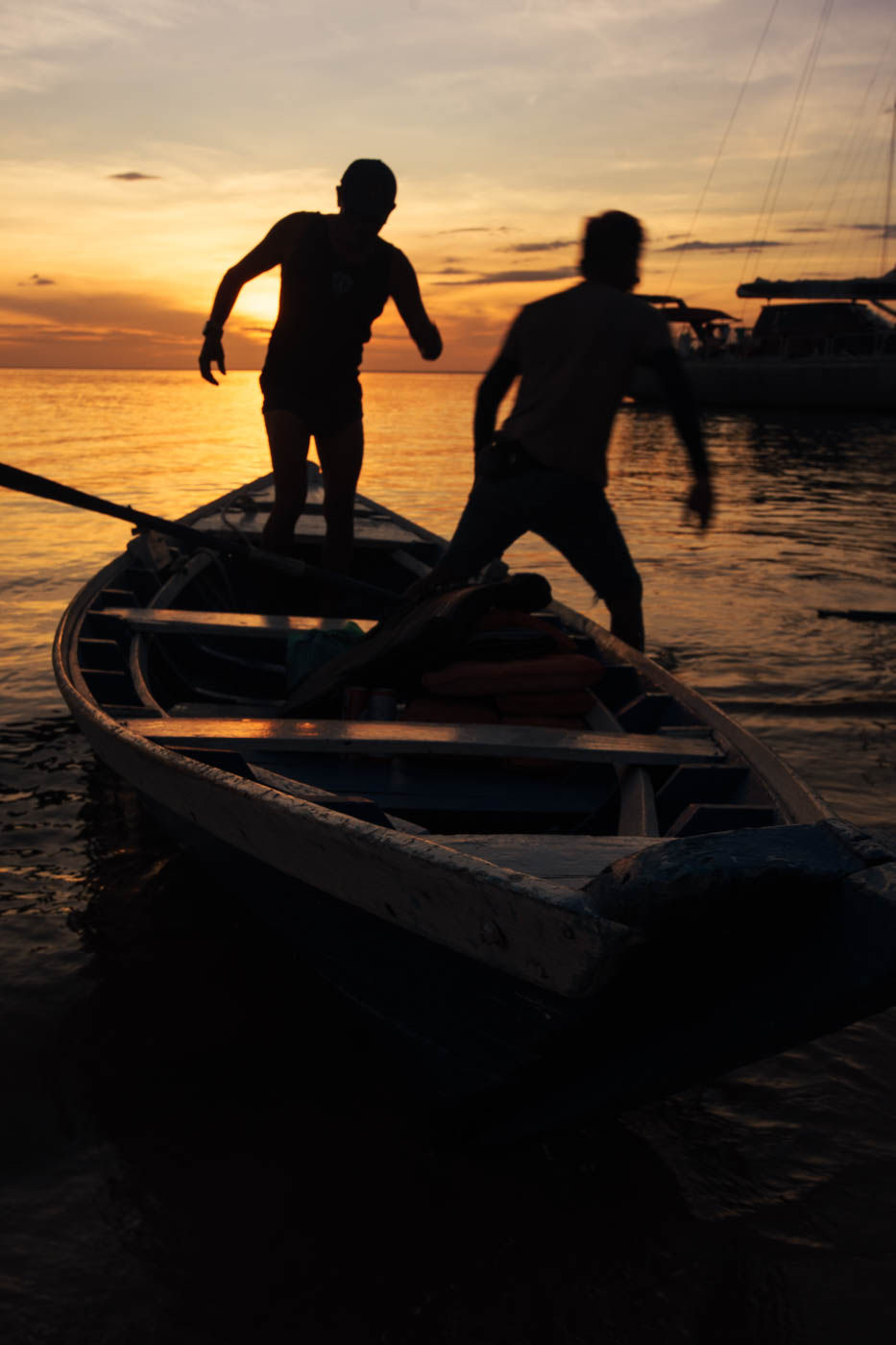 Ribeirinhos sobre uma canoa durante o pôr do sol.