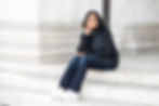 Dr. Mia Smith-Bynum sitting on steps with a black jacket, black shirt, jeans, pearl necklace, and pearl earrings.