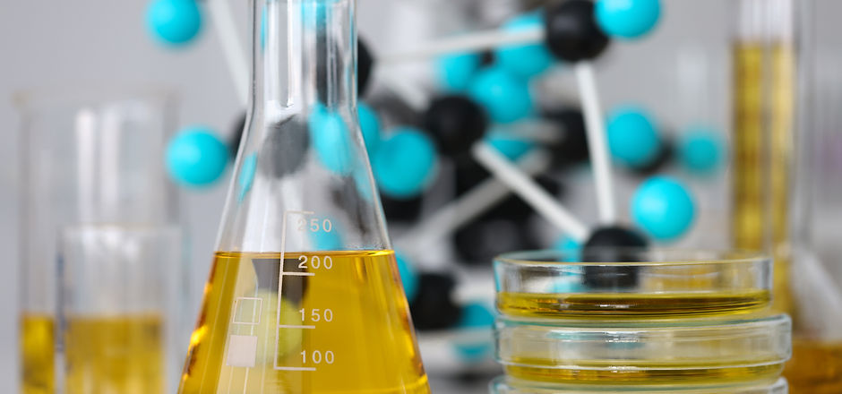 Glass test tubes with yellow viscous liquid stand on table in chemical laboratory closeup.