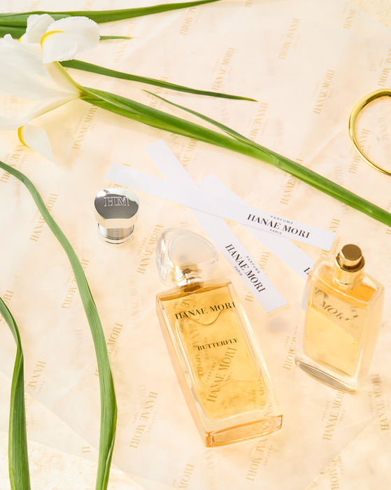 Flacon de parfum Hanae Mori posé dans un feuillage vert, photographie packshot nature