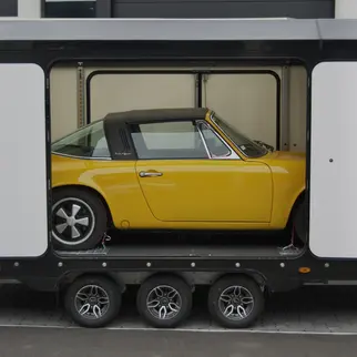 Side view of a yellow Porsche 912 Targa in a Brian James trailer

