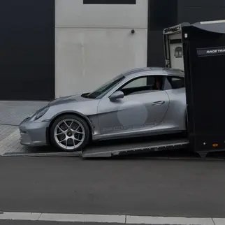 Grey Porsche 911 992 S/T exiting a Brian James enclosed trailer
