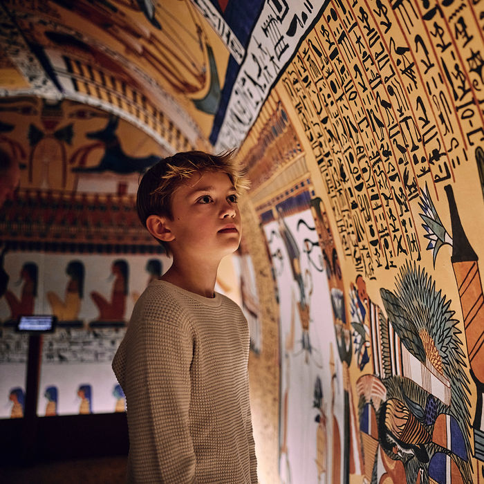 A boy standing in full-scale replica of Sennedejem’s richly decorated burial chamber.