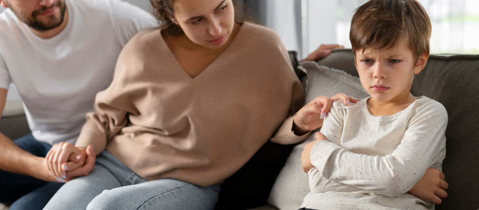 Um garoto com rosto contrariado e os pais olhando para ele tentando conversar.