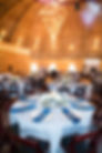 An event space full of tables set with blue and white linens and flowers