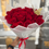 Thumbnail: Hand holding a bouquet of 100 red roses wrapped with white paper.