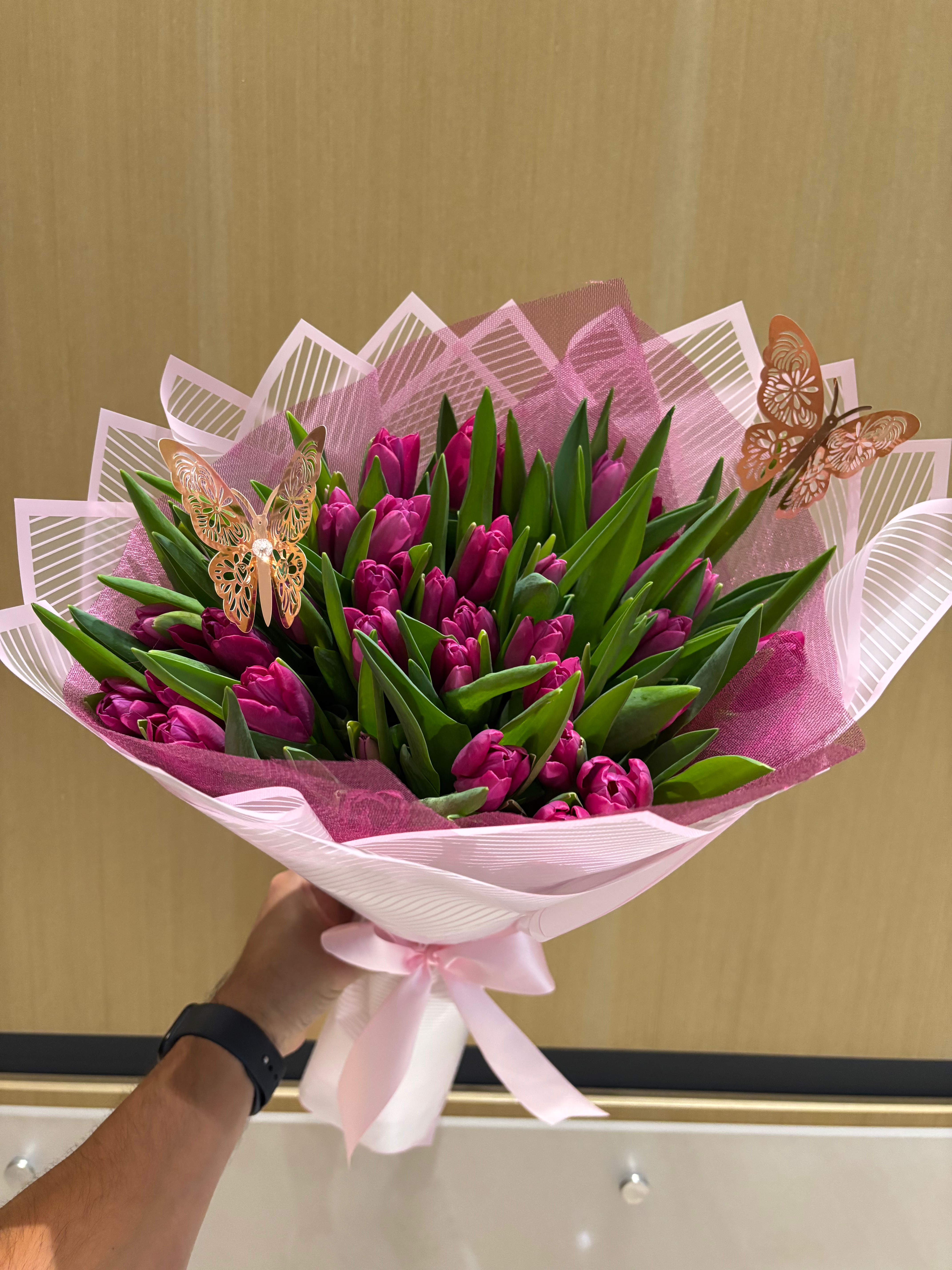 Hand holding beautiful bouquet of purple tulips with decorative butterflies, Doral Blooms