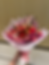 Bouquet of red roses and tulips with butterfly decorations on pink wrap.