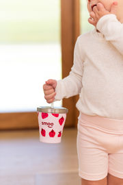 a child is holding a smoo cup with strawberries on it