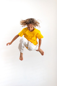 Kids lifestyle photography featuring a child jumping against a clean white studio background.