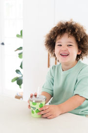 a young boy is holding a cup that says imoo on it