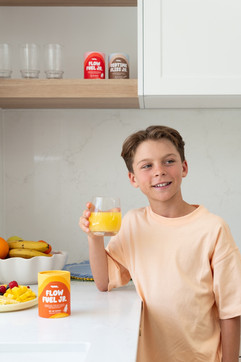 Kids lifestyle product photography featuring a child enjoying a Voomie Jr wellness drink in a bright kitchen setting, shot by MNDY Photography