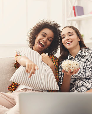 To unge kvinder ser noget på en computer og spiser popcorn
