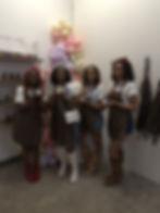 Four smiling women in aprons presenting products at an event
