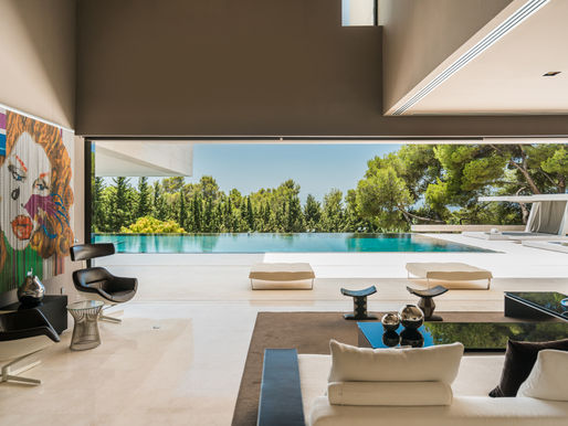 Luxury modern villa living area opening onto an infinity pool and garden, designed for seamless indoor-outdoor living.