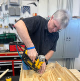 Tool Tech Ryan using a nail gun on a team's wooden prototype