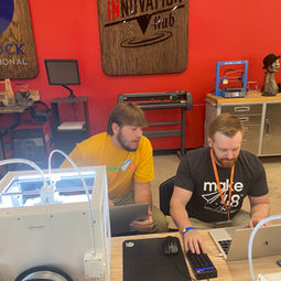 tool tech and a team member in yellow team shirt sitting next to each other working at a laptop