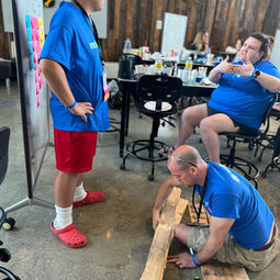 team of three in blue team shirts working together with wood on the floor