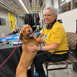 umkc volunteer sitting in a chair with a brown dog up on her lap
